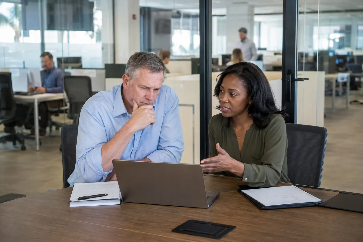 Two business leaders discuss security concerns in a glass office meeting room.
